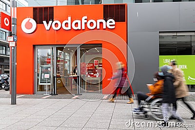 Facade and shop window of the Vodafone store with passengers in motion blur in front. Editorial Stock Photo