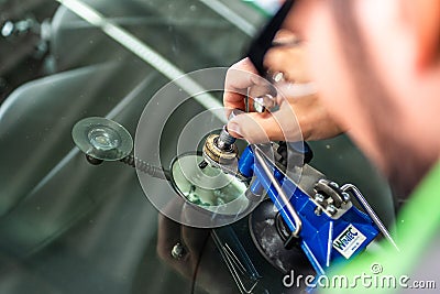 Koblenz Gerrmany 04.04.2018 man using repairing equipment to fix damaged cracked windshield at wintec company Editorial Stock Photo