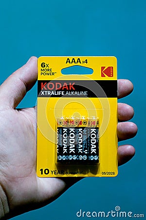 Kodak battery pack with 10 year warranty. Kodak promises 6 x more power. Battery pack held in hand with a blue background Editorial Stock Photo