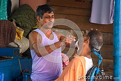 Indian barber shaving man on the street in Kolkata. India Editorial Stock Photo