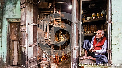An Indian vendor selling a variety of pottery in his rustic shop on the streets of the Editorial Stock Photo
