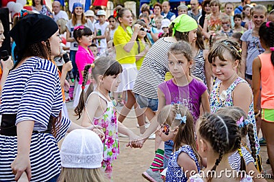Girl dressed in a pirate costume leads roundelay with group of children Editorial Stock Photo