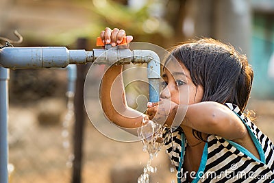 Kon Tum, Vietnam - Mar 29, 2016: A little girl drink water from outdoor tap which water supplied by drilling well in Central Highl Editorial Stock Photo