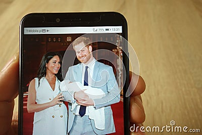 KONSKIE, POLAND - May 18, 2019: hand holding smartphone with photo of Prince Harry and Meghan Markle with baby Editorial Stock Photo