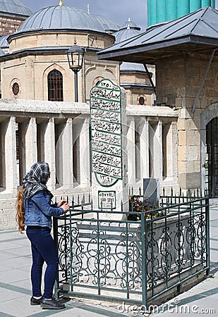 Unidentified Turkish Woman with Scarf praying at Old Ottoman Era Grave behind the Mevlana Museum Mosque Editorial Stock Photo