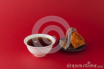 Korean fruit punch or tea - Sujeonggwa on a red background with gradient. It is made from dried persimmons with pine nuts Stock Photo