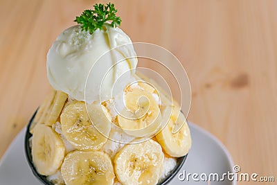 Korean style bing su fresh banana shaved ice on wood table . Stock Photo