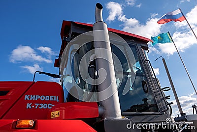 Kostanay, Kazakhstan, 2019-10-23, Cabin of a red tractor of the Kirovets K-730 and flags against the sky with clouds. The concept Editorial Stock Photo