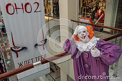 19-08-16, Kostanay, Kazakhstan. A guy in an IT suit stands next to a poster for a new film. A very scary clown with teeth leaned Editorial Stock Photo