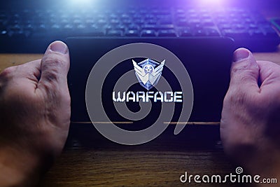 Kostanay, Kazakhstan, November 02, 2021.In hand is mobile phone with screensaver logo popular Warface game Editorial Stock Photo