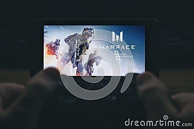 Kostanay, Kazakhstan, November 02, 2021.In hand is mobile phone with screensaver logo popular Warface game Editorial Stock Photo
