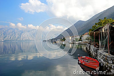 Kotor fjord. Red boat, mountains, clouds. Ancient Perast Stock Photo