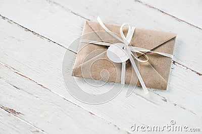 Kraft envelope with teg with heart and ribbon on white wooden tabletop Stock Photo