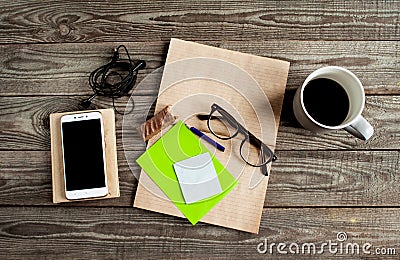 With kraft Freelance work space notebook, eyeglasses, pencil, cup of coffe, bitten chocolate, smart phone, headphones, Stock Photo