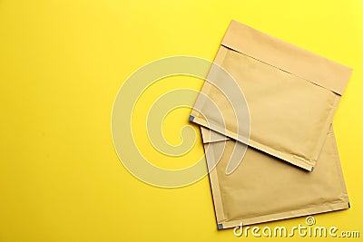 Kraft paper envelopes on yellow background, flat lay. Space for text Stock Photo