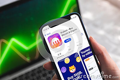 Kraken crypto currency wallet app. Hand with smartphone, logo on the screen. Stock chart background photo Editorial Stock Photo