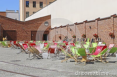 KRAKOW,POLAND - AUGUST 16, 2018: Street cafe corner with deck chairs in front of old brick wall. Kazimierz district Editorial Stock Photo