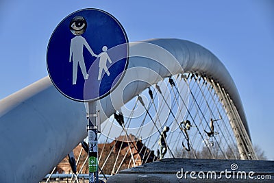 Krakow, Poland. Blue Circular Street Sign with adult holding childs hand. Father Bernatek’s Bridge behind. Editorial Stock Photo