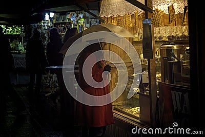 Krakow, Poland - December 22, 2014: A girl in red coat holding umbrella in front of waffle shop during Christmas eve holidays in Editorial Stock Photo