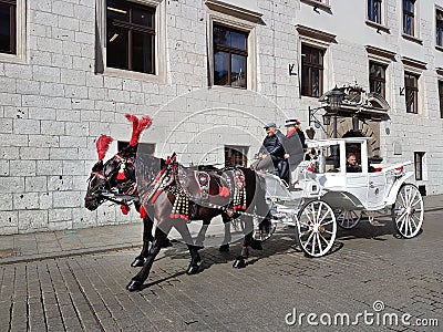 Krakow, Poland - 09.13.2017: Morning town after the rain. Bright sunny day. A horse-drawn carriage with a white coach drives touri Editorial Stock Photo