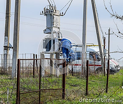 Electricians repair electrical transformer. Repair team on the road Editorial Stock Photo