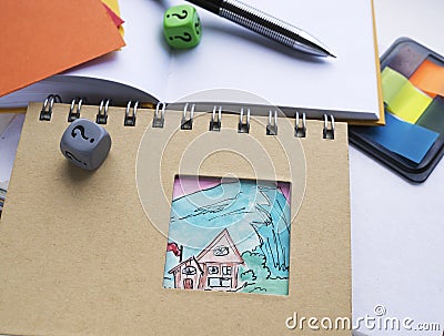 Choosing property. Dices with a question mark lying on a notebook with a house painted on it. Stock Photo