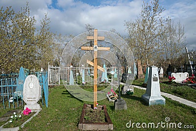 A wooden cross among the graves at the Troitskoye cemetery 1842 of the city of Krasnoyarsk, in the spring. Editorial Stock Photo