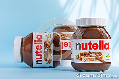 Jars of nutella on a blue background with hard shadows from sunlight. Editorial Stock Photo