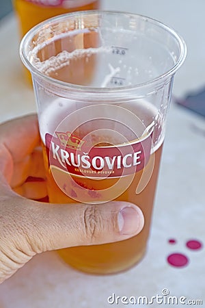 Hand holding krusovice beer in plastic glass Editorial Stock Photo