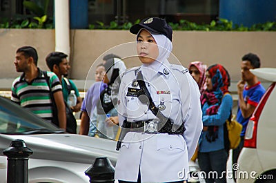 Asian police woman stands along the road in a white uniform, cap and hijab Editorial Stock Photo