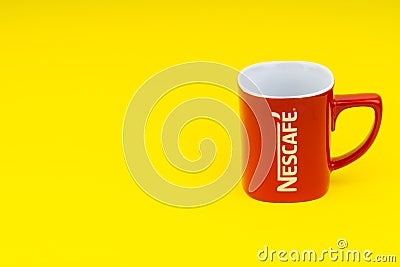 Red Nescafe mug isolate on yellow background Editorial Stock Photo