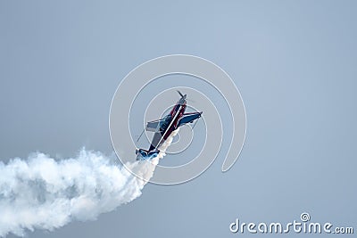 Silhouette of an airplane with trail of smoke behind against background of blue sky. Editorial Stock Photo