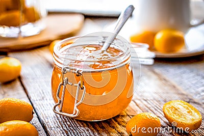 Kumquat on plate and jam in jar at wooden table Stock Photo