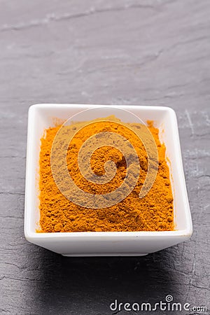 Kurkuma spice powder in white bowl on dark slate background. Stock Photo