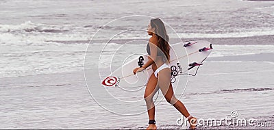 KUTA, BALI, INDONESIA - OCTOBER 17, 2017: The surfer girl walked by the board on the sandy beach. Exotic brown-skinned young woman Editorial Stock Photo