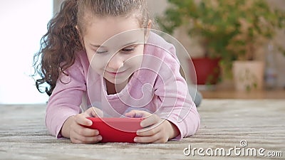 Kute baby's met een mobiele telefoon of tablet Kleine meid geeft haar gratis tijd door met een mobiel spel en knuffels stock videobeelden Kute baby's met een mobiele telefoon of tablet Kleine meid geeft haar gratis tijd door met een mobiel spel en knuffels stock videobeelden