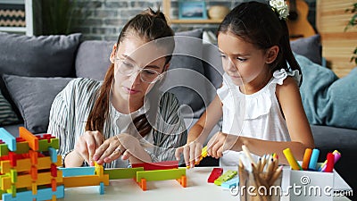 Kute kleine meid die thuis speelt met een verzorgende moeder die plezier heeft met houten speelgoed stock footage Kute kleine meid die thuis speelt met een verzorgende moeder die plezier heeft met houten speelgoed stock footage