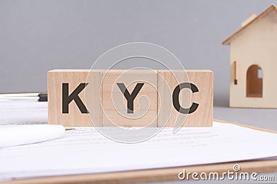 KYC text made of wooden blocks on gray background with a small wooden model house Stock Photo