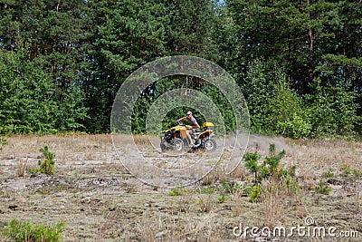Kyiv- September 2019 Man riding a yellow quad ATV all terrain vehicle on a sandy forest. Extreme sport motion, adventure, tourist Editorial Stock Photo