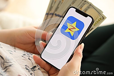 KYIV, UKRAINE - APRIL 1, 2024 Qzone icon on smartphone screen and money in female hand Editorial Stock Photo