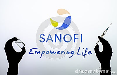 Kyiv, Ukraine - December 22, 2020: Backlit single shot image of Sanofi logo on tv screen .with a hand holding an Covid-19 vaccine Editorial Stock Photo