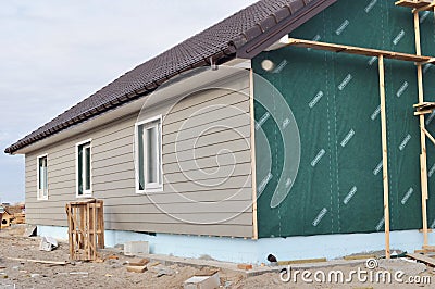 Building house with wall insulation, waterpfoof membrane, plastic siding, guttering and foundation insulation with styrofoam. Stock Photo