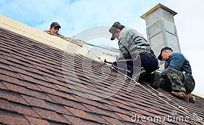 Roofer contractors are installing dimensional asphalt shingles from bottom up on the rooftop with Editorial Stock Photo