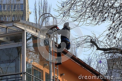 The worker climbs the side stairs to the roof of the building. Editorial Stock Photo