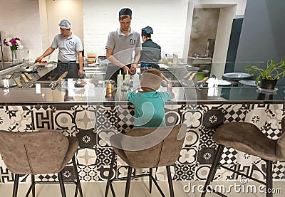 Cooks and chef cooking food for children at open space kitchen of urban restaurant Editorial Stock Photo