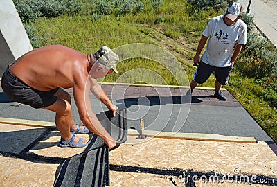 KYIV, UKRAINE - October, 09, 2019: Roofer laying asphalt shingles on new roof. Roofer contractors installing asphalt shingles on Editorial Stock Photo