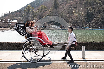 Chinese tourists boarded a rickshaw pulled by a young man Editorial Stock Photo
