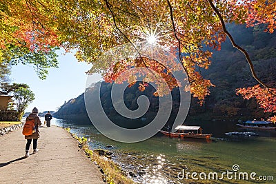 Unidentified tourists enjoy autumn colors along Hozu-gawa river at Arashiyama Editorial Stock Photo