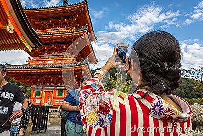 Kyoto, Japan - Sept 20th 2018 - A woman dressing like a geisha taking a picture of a temple in a sunny blue sky day in Kyoto, Editorial Stock Photo