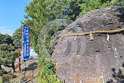 Giant megalith rock called iwakura rock in shintoism adorned with a shimenawa rope in the JÃ´juin temple of Sasebo. Editorial Stock Photo